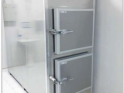 Mortuary Refrigerator — Two Cells, three-quarter view with doors closed, top-mounted temperature display, tiled room
