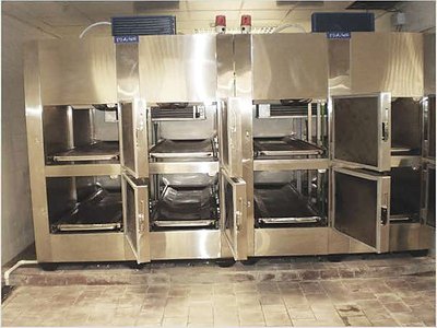 Mortuary Refrigerator — Six Cells, installed bank with several doors open showing body trays